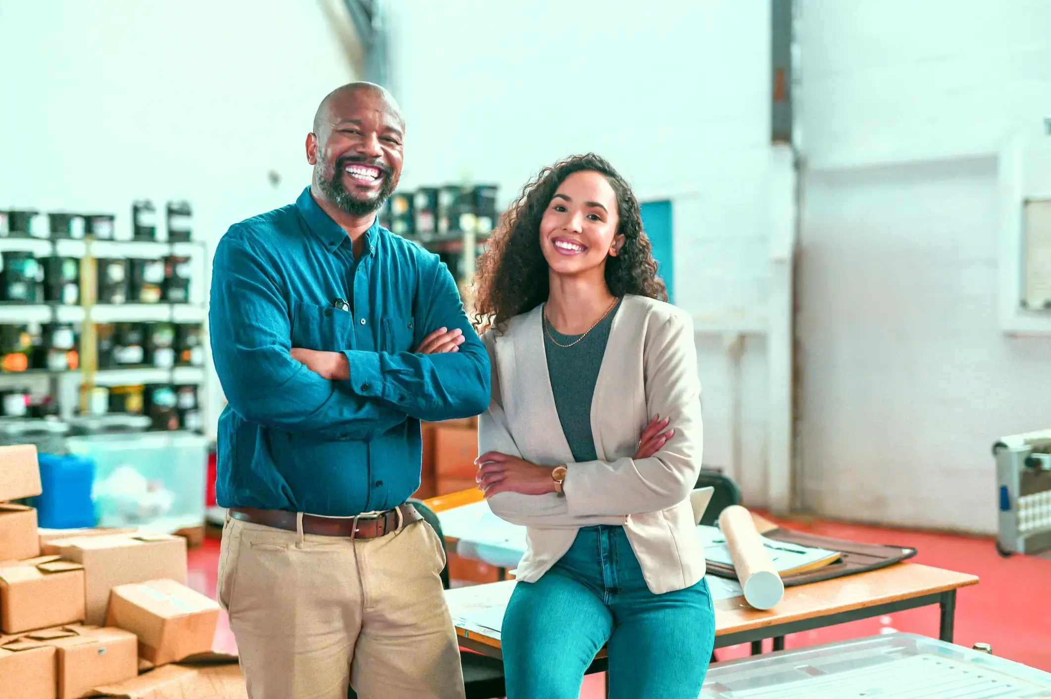 Business partners in a warehouse, smiling with confidence and collaboration.
